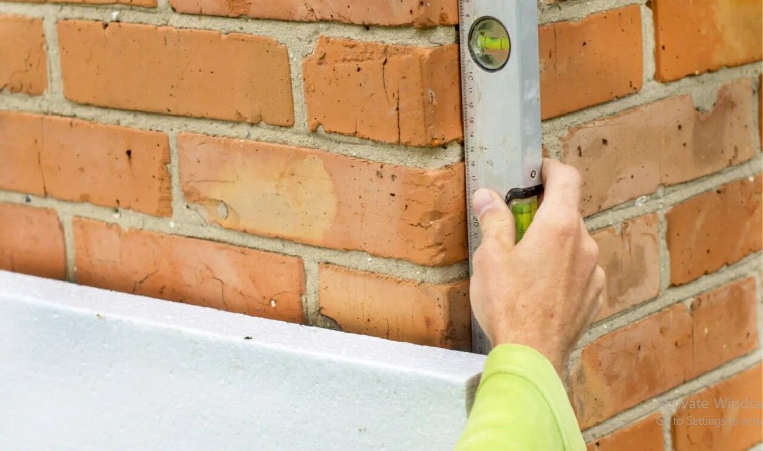A person is measuring a brick wall with a level.