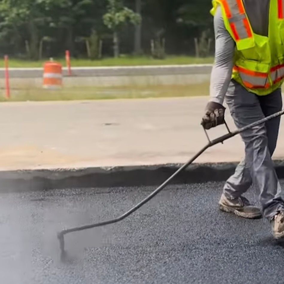 Worker applying sealcoating to asphalt in St. Louis to protect pavement and extend parking lot 