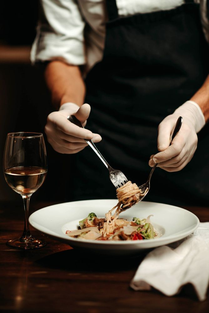 A chef is serving a plate of food with a fork and spoon.