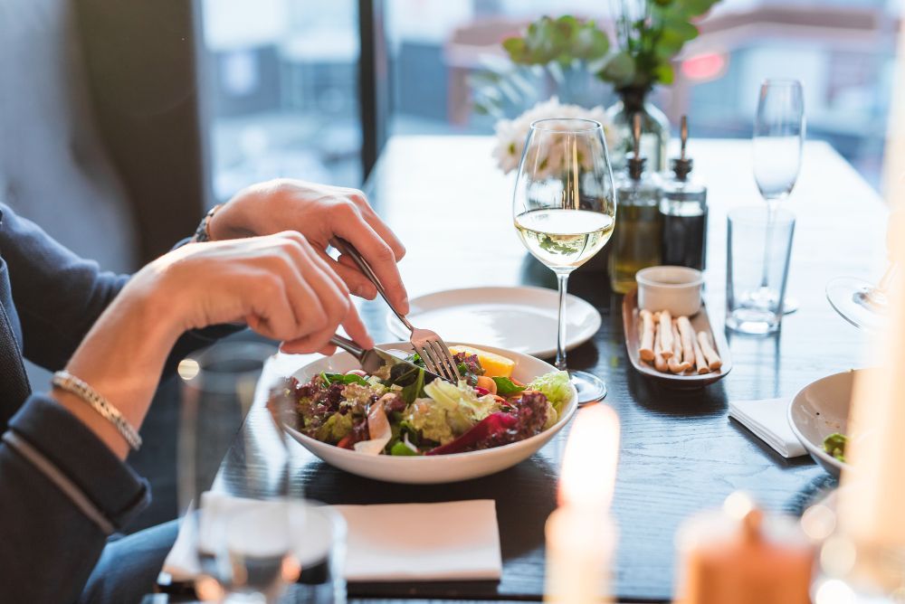 A woman is sitting at a table eating a salad.