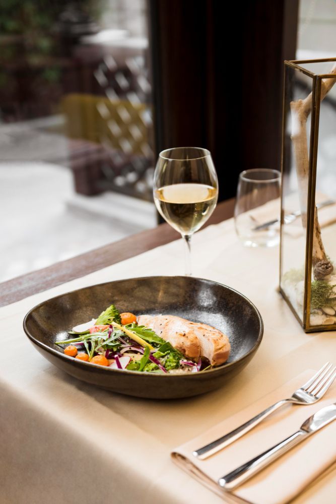 A plate of food and a glass of wine on a table.