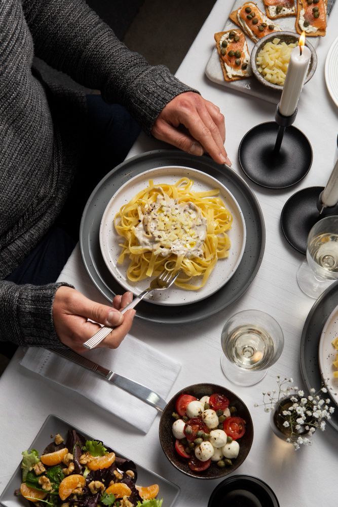 A man is sitting at a table eating a plate of pasta.