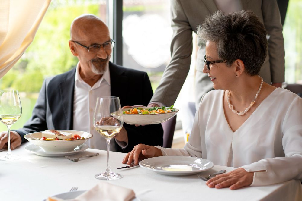 A man is serving a salad to a woman at a restaurant.