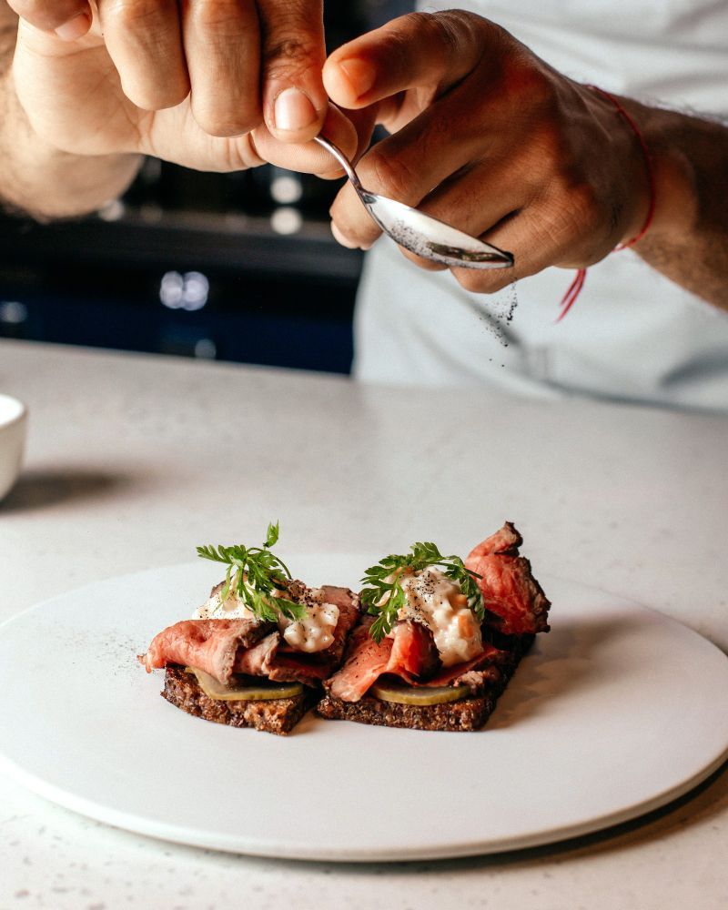 A person is holding a spoon over a plate of food.