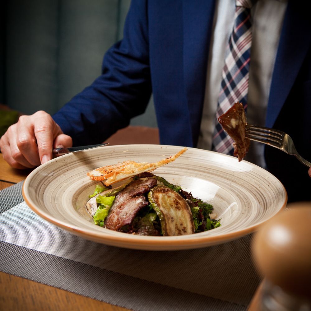 A man in a suit and tie is eating a plate of food