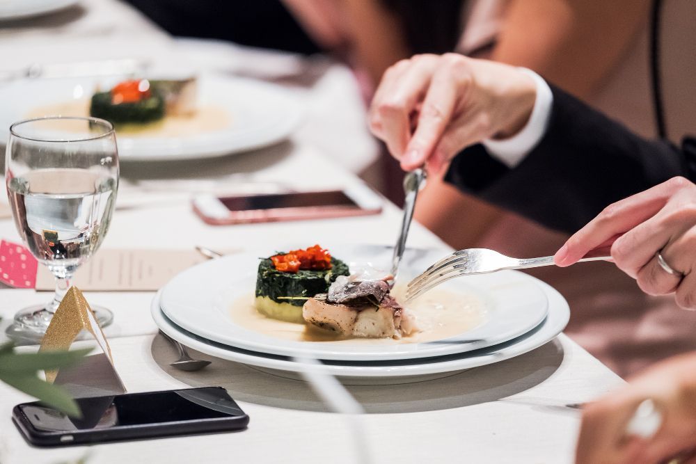 A man and woman are sitting at a table eating food.