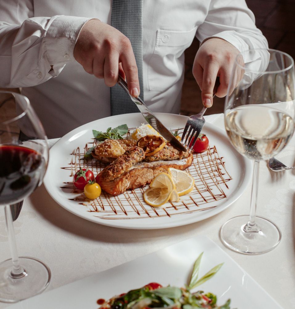 A man is cutting a piece of meat on a plate