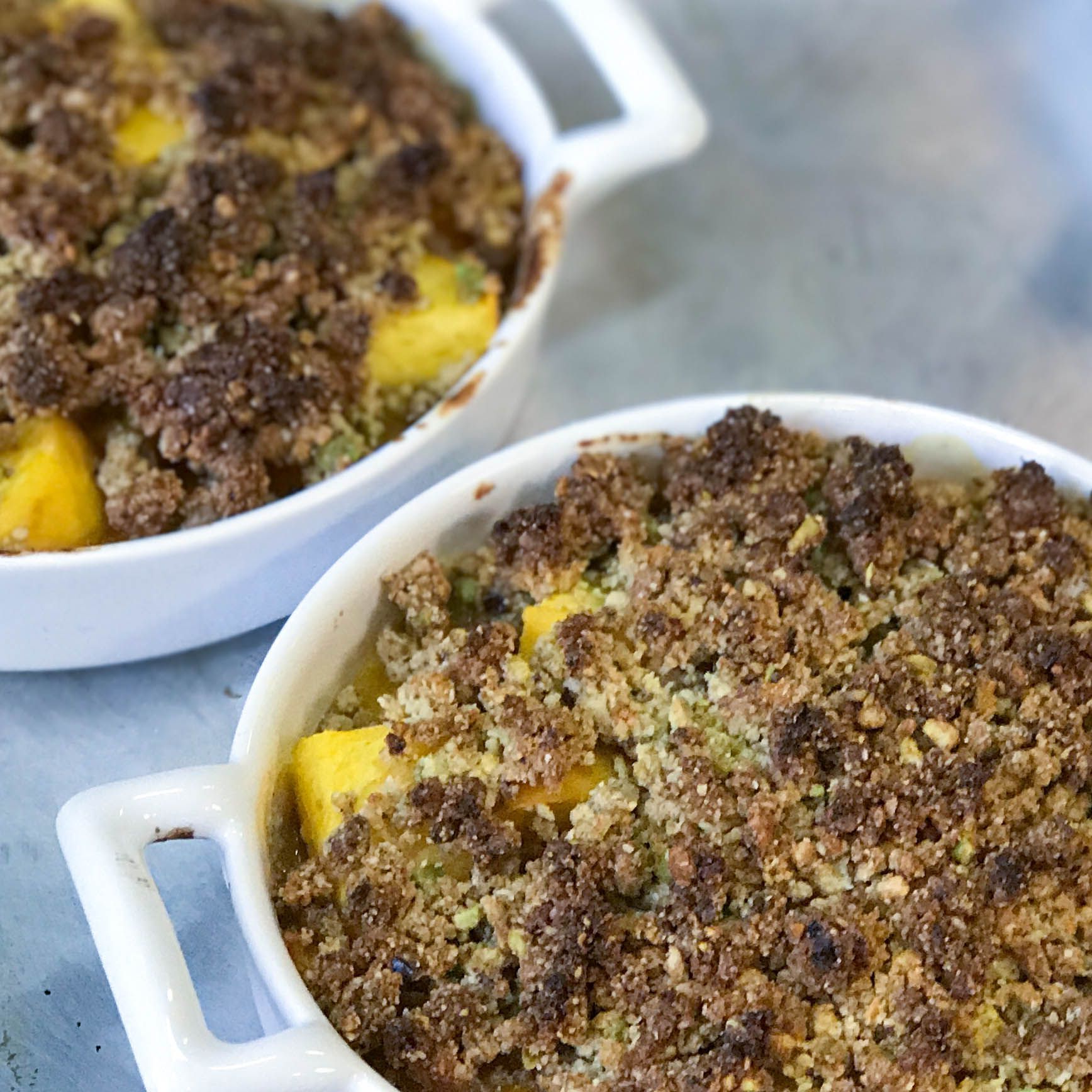 Two bowls of food with crumb topping on a table