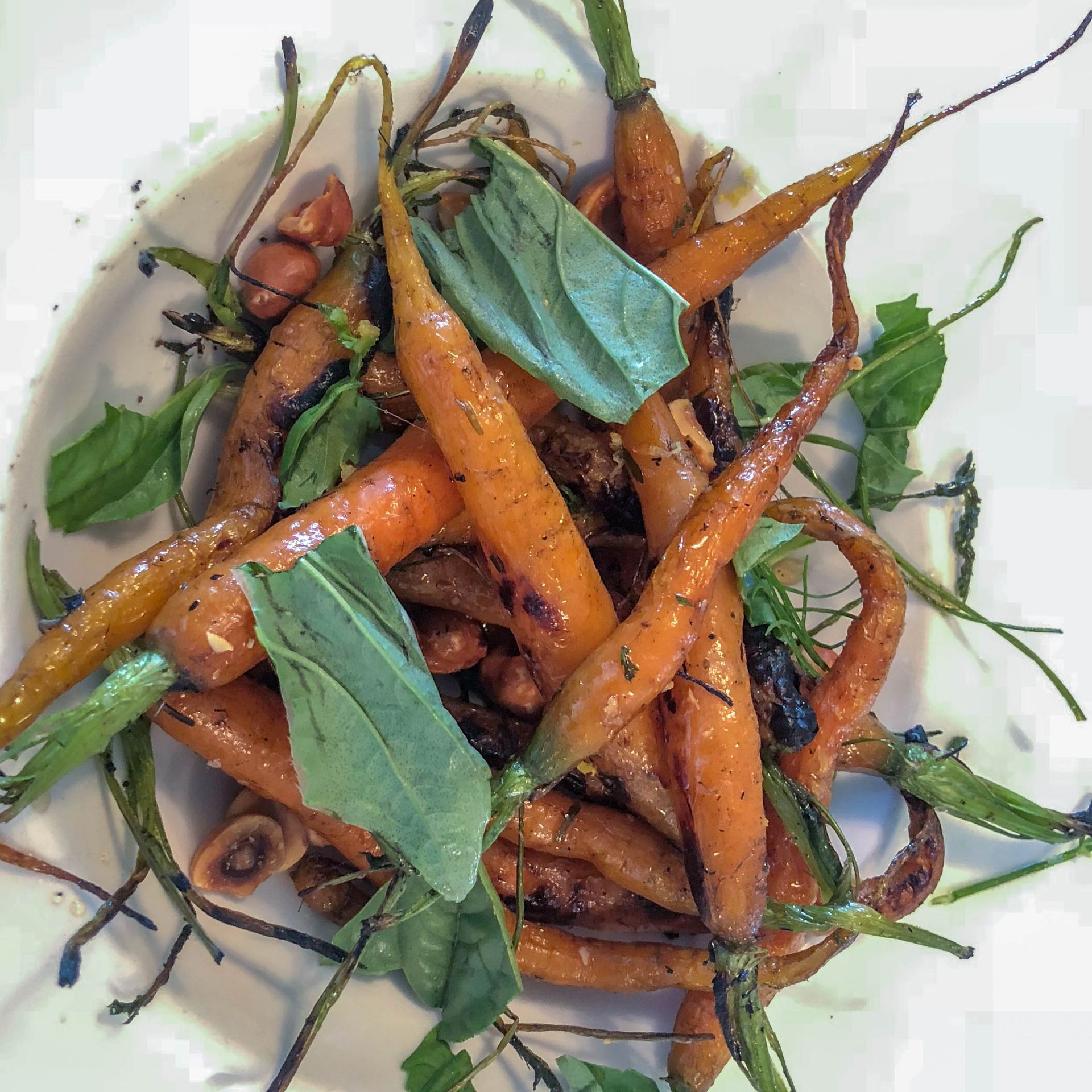 A white plate topped with carrots and green leaves