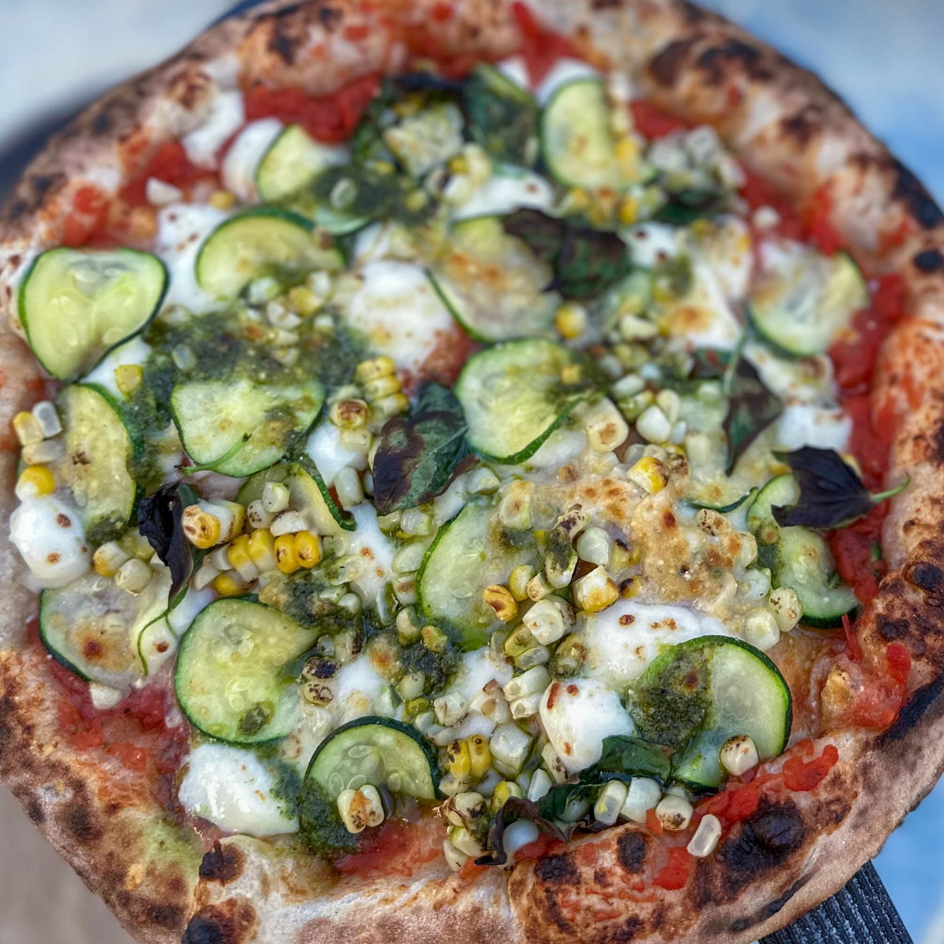 A pizza with a lot of vegetables on it is being held in someone 's hand.