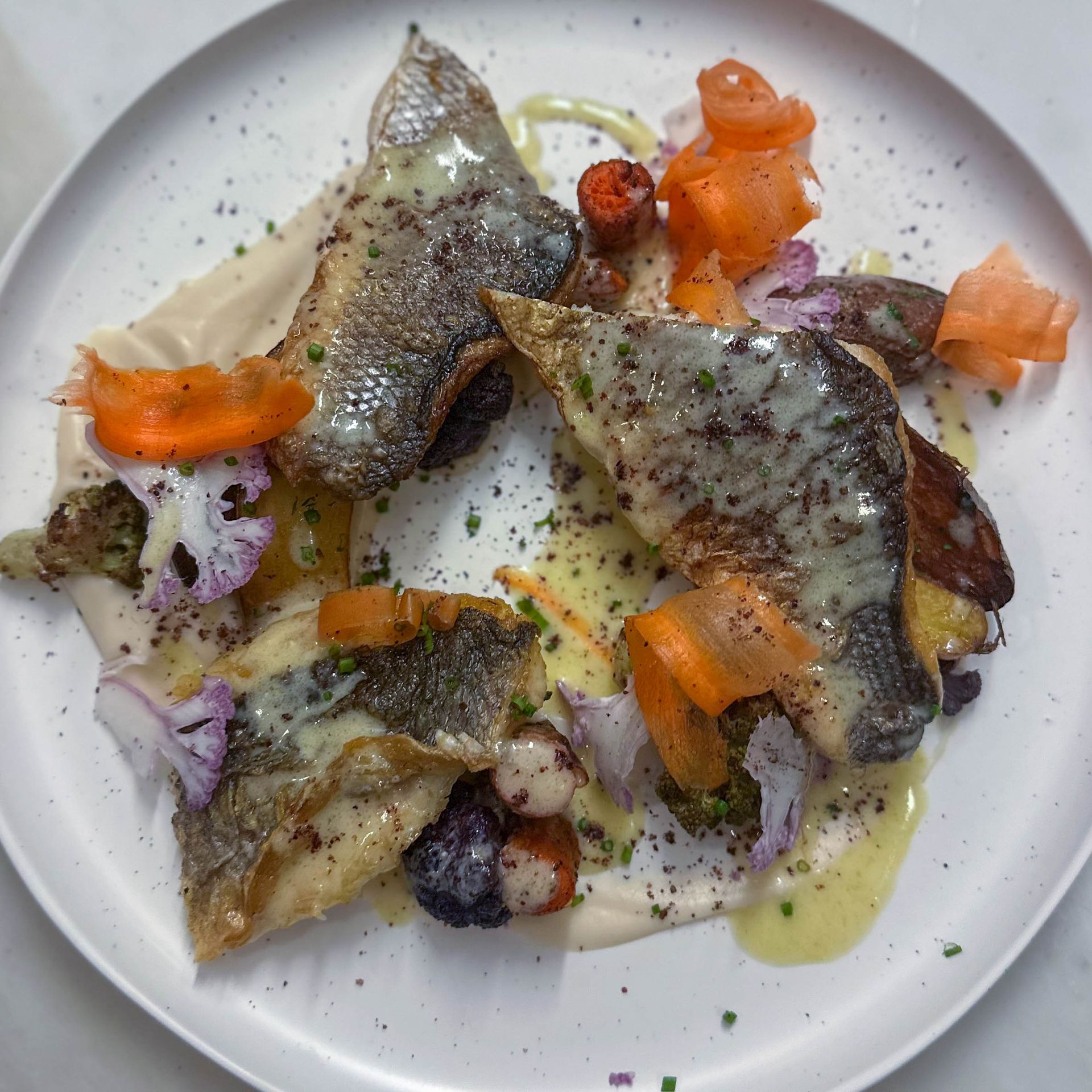 A white plate topped with meat and vegetables on a table