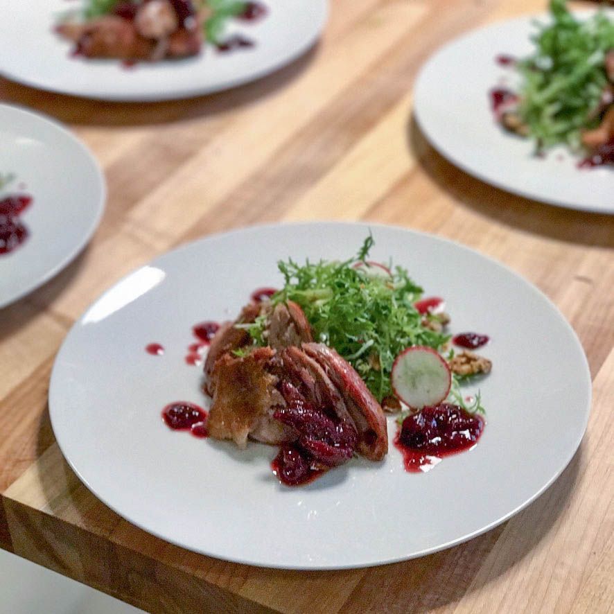 A white plate topped with meat and vegetables on a wooden table.