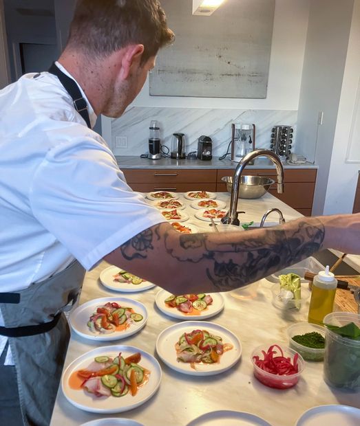 A man with a tattoo on his arm prepares food in a kitchen