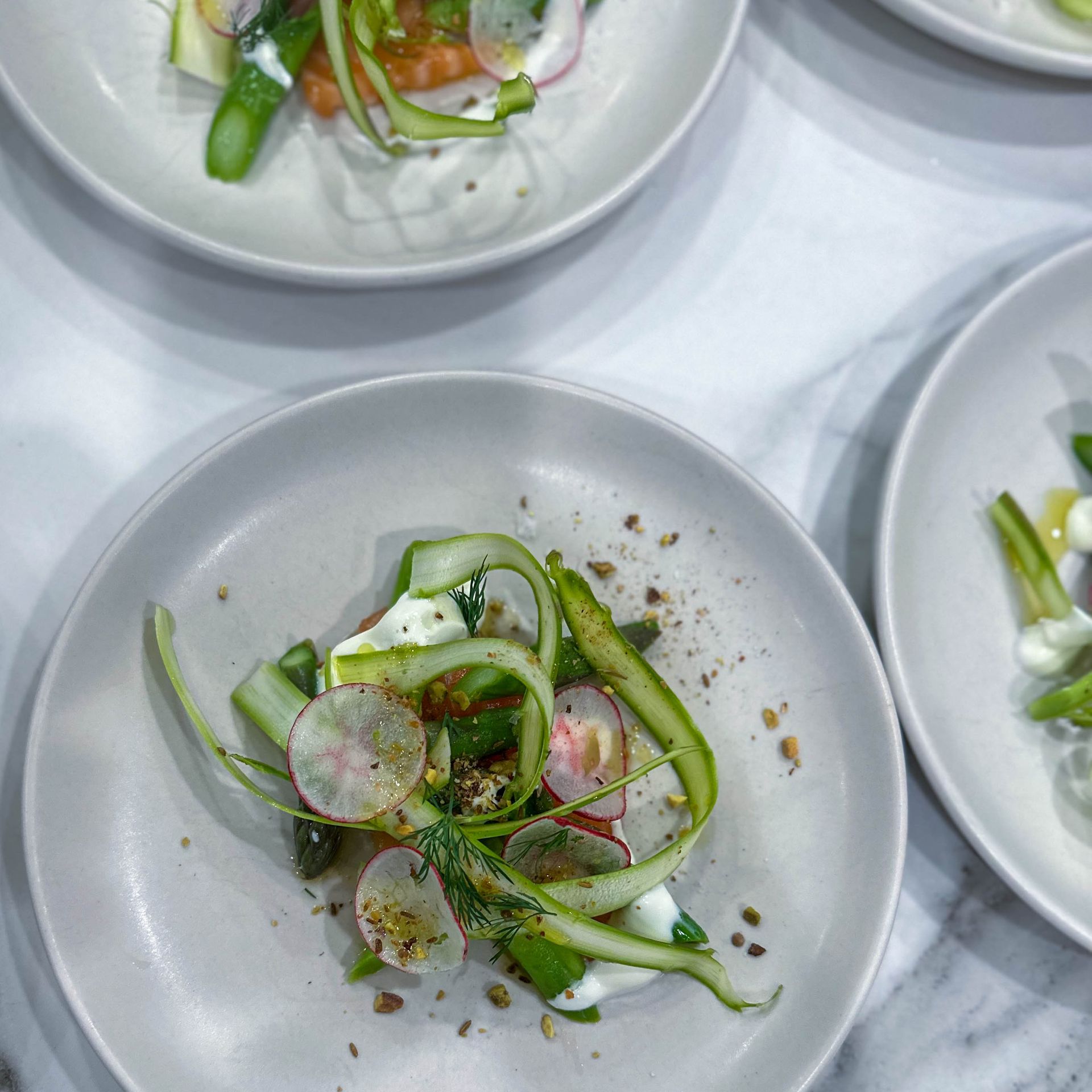 Three plates of food with vegetables on them are on a table.