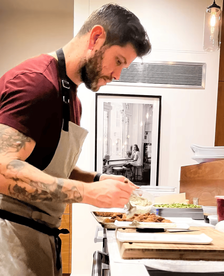 A man in an apron is preparing food in a kitchen.