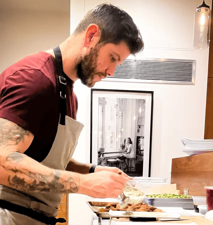 A man in an apron is preparing food in a kitchen.