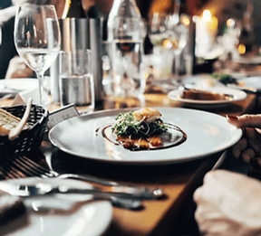 A person is holding a plate of food on a table.