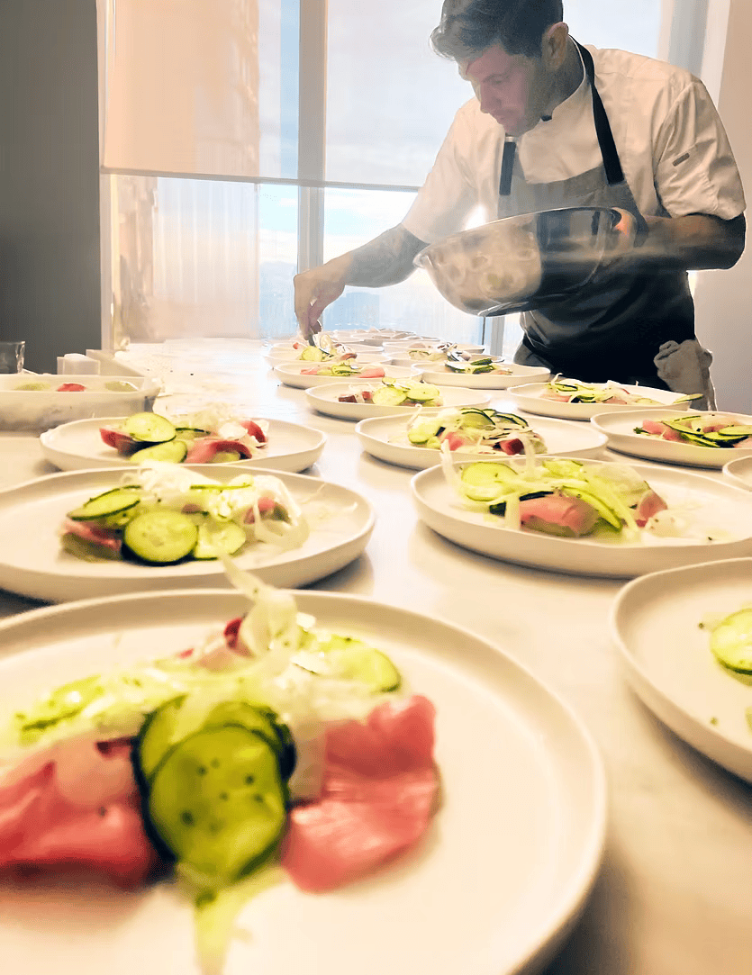 A man is preparing food on a table with plates of food.