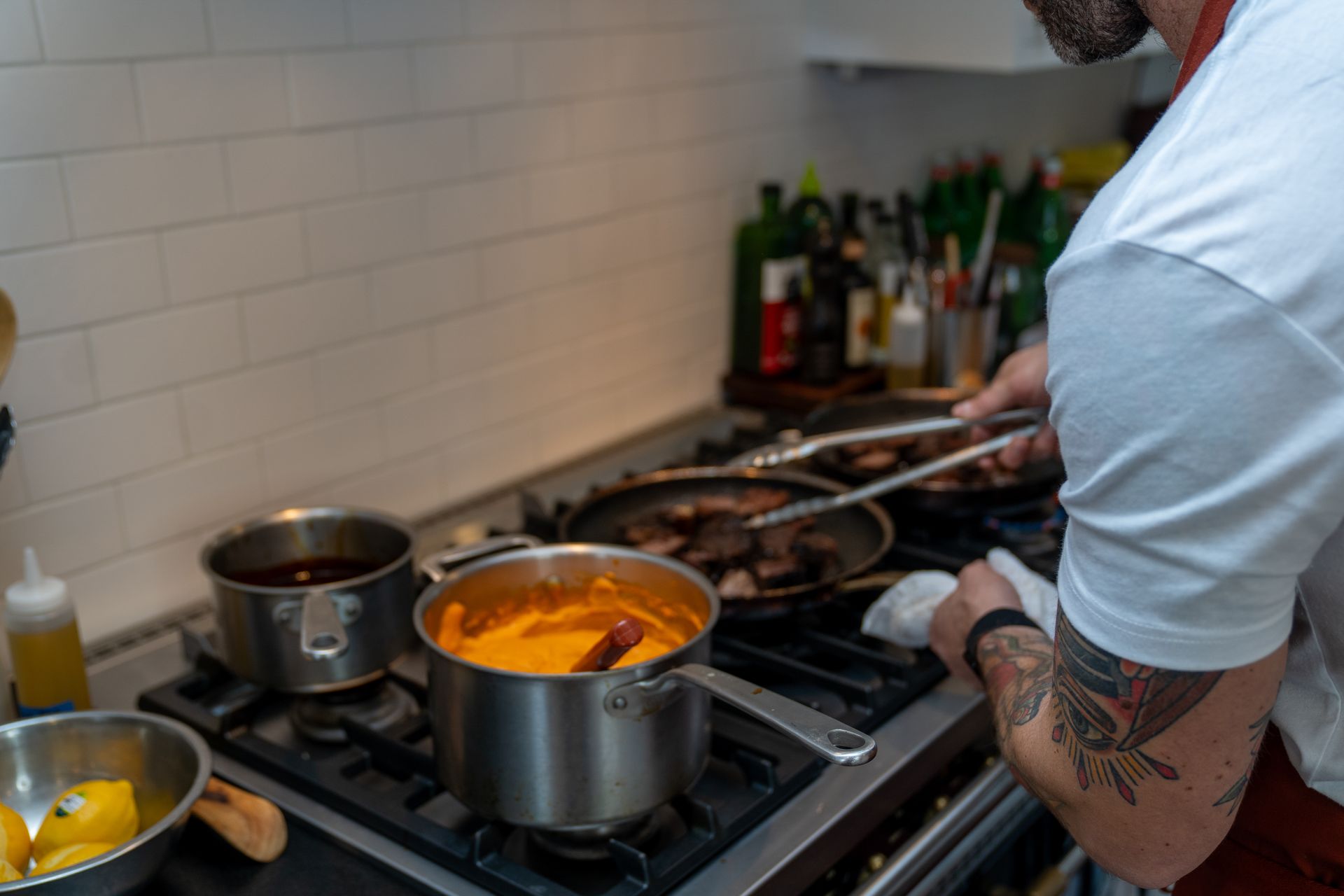 A man is cooking food on a stove in a kitchen.