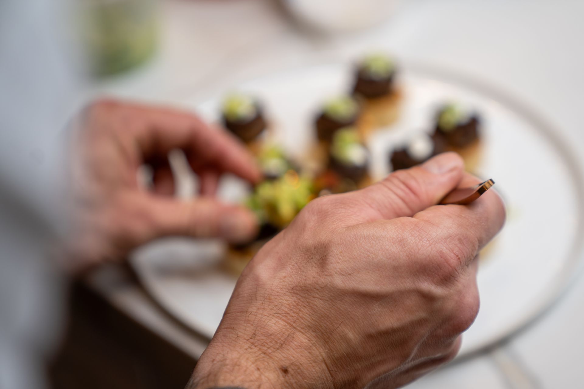 A close up of a person 's hands preparing food on a plate.