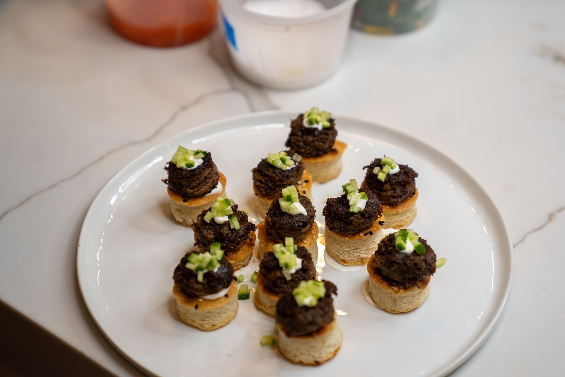 A white plate topped with small appetizers on a counter.