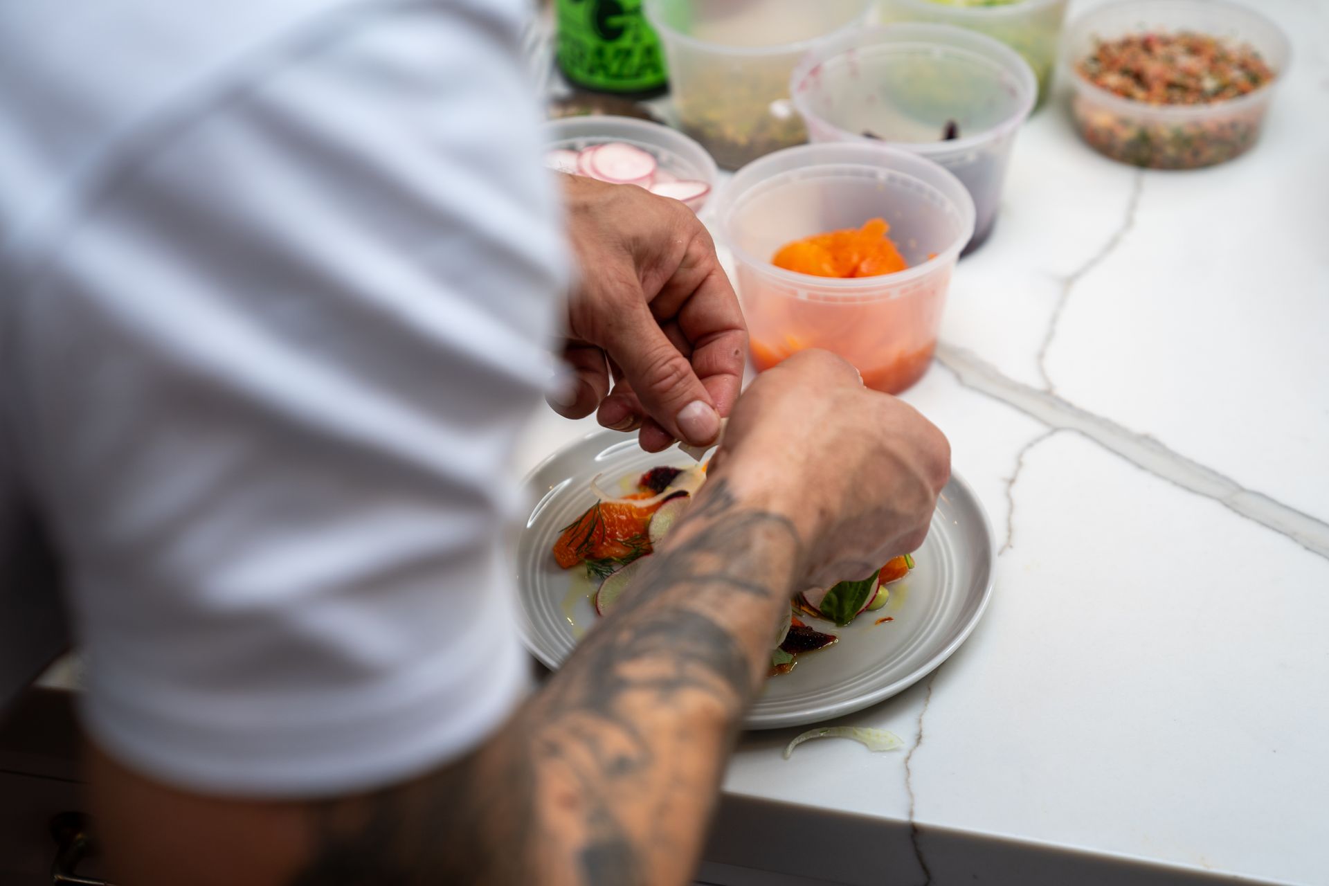 A man with a tattoo on his arm is preparing food on a plate.
