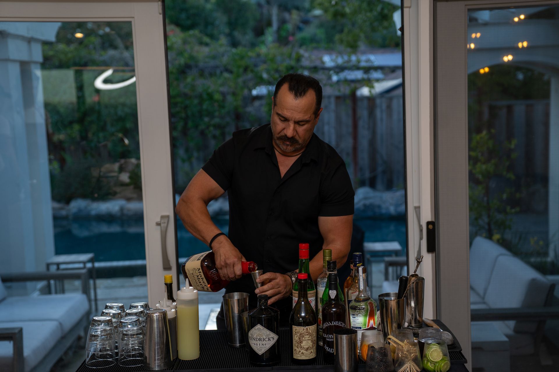 A man is pouring a drink into a glass at a bar.