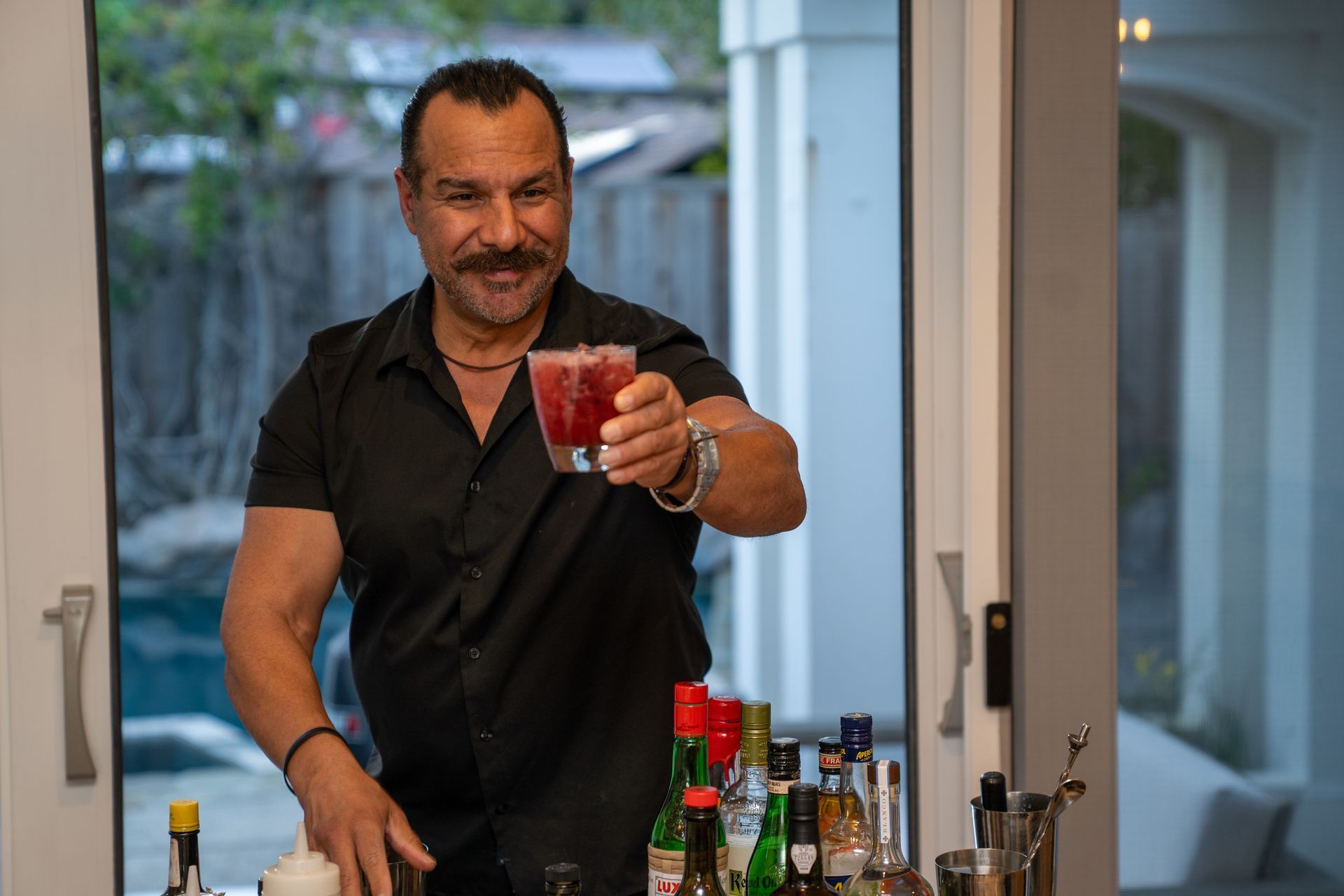 A man is holding a glass of red liquid in his hand.