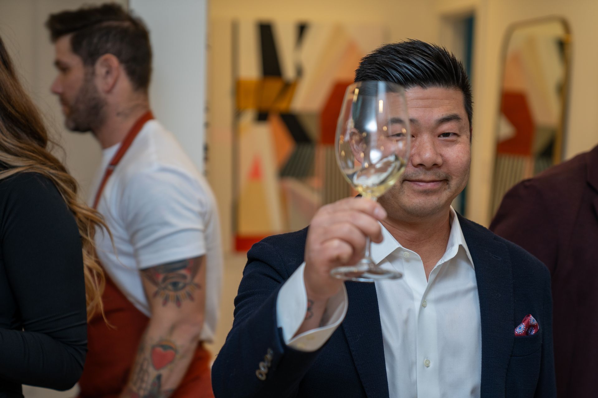 A man in a suit is holding a glass of wine.
