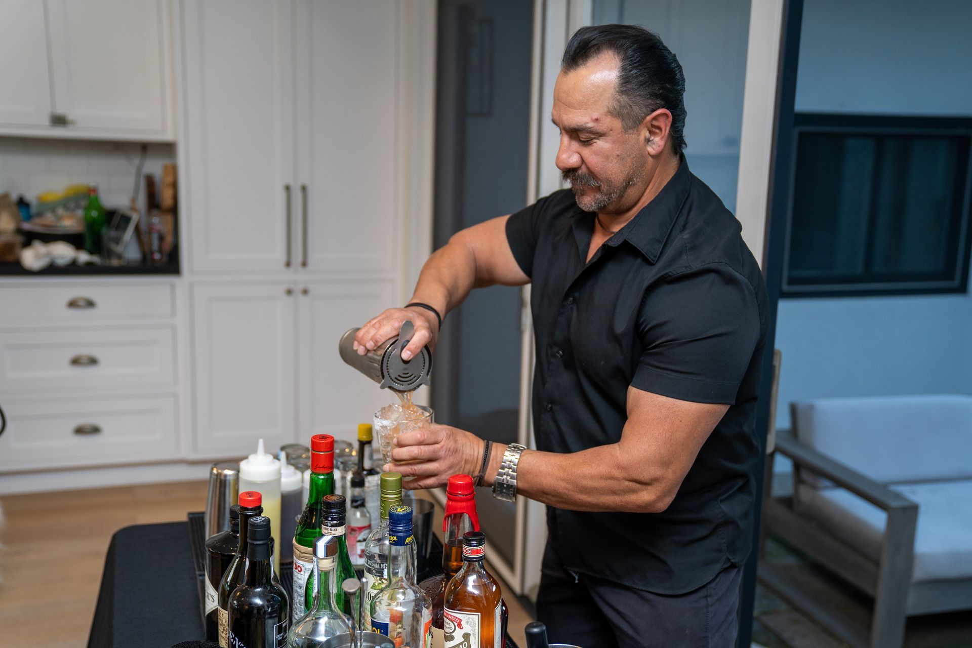 A man is pouring a drink into a glass at a bar.