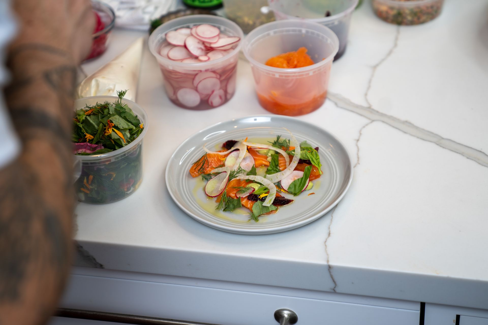 A plate of food is sitting on a counter next to containers of food.