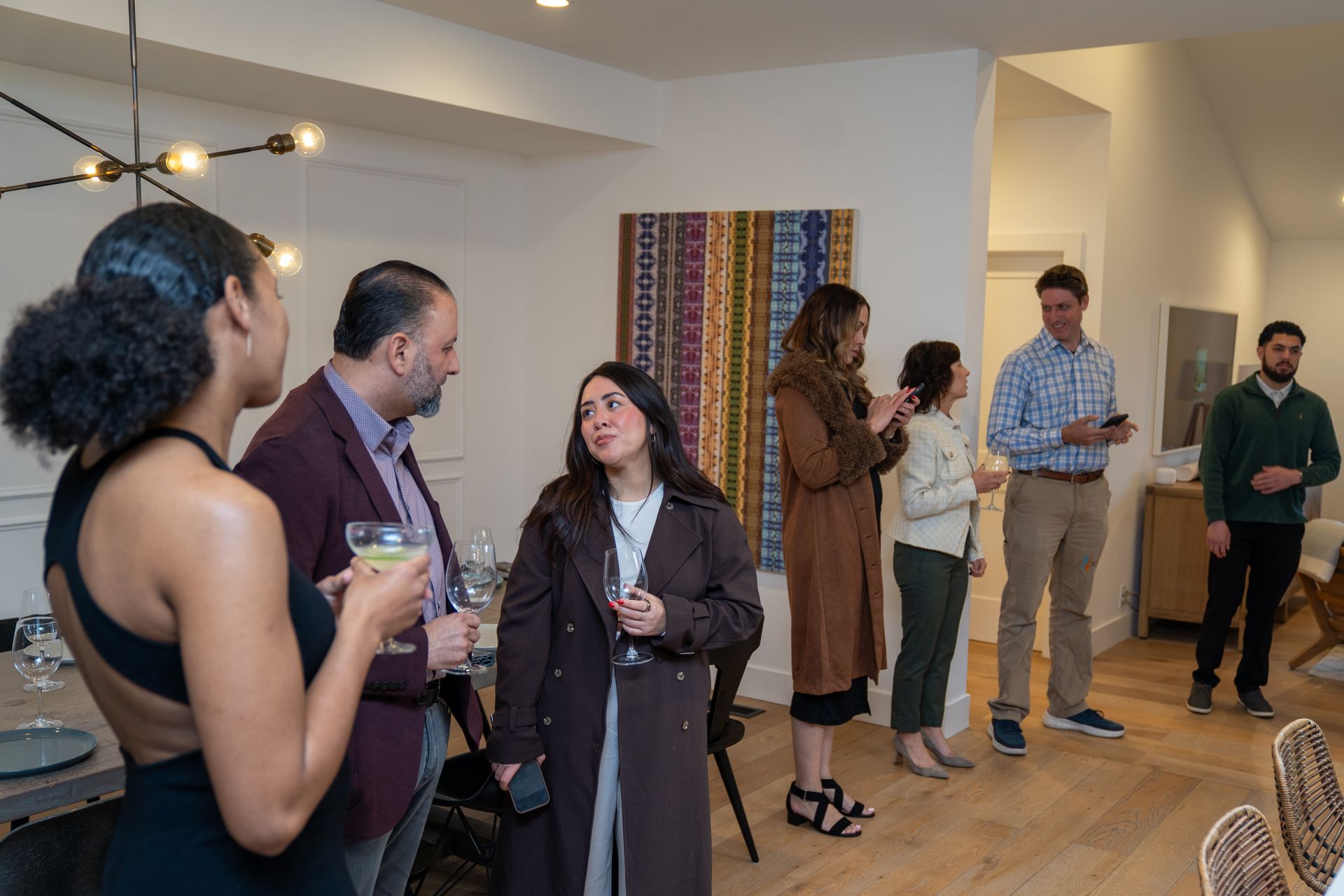 A group of people are standing in a room talking to each other.