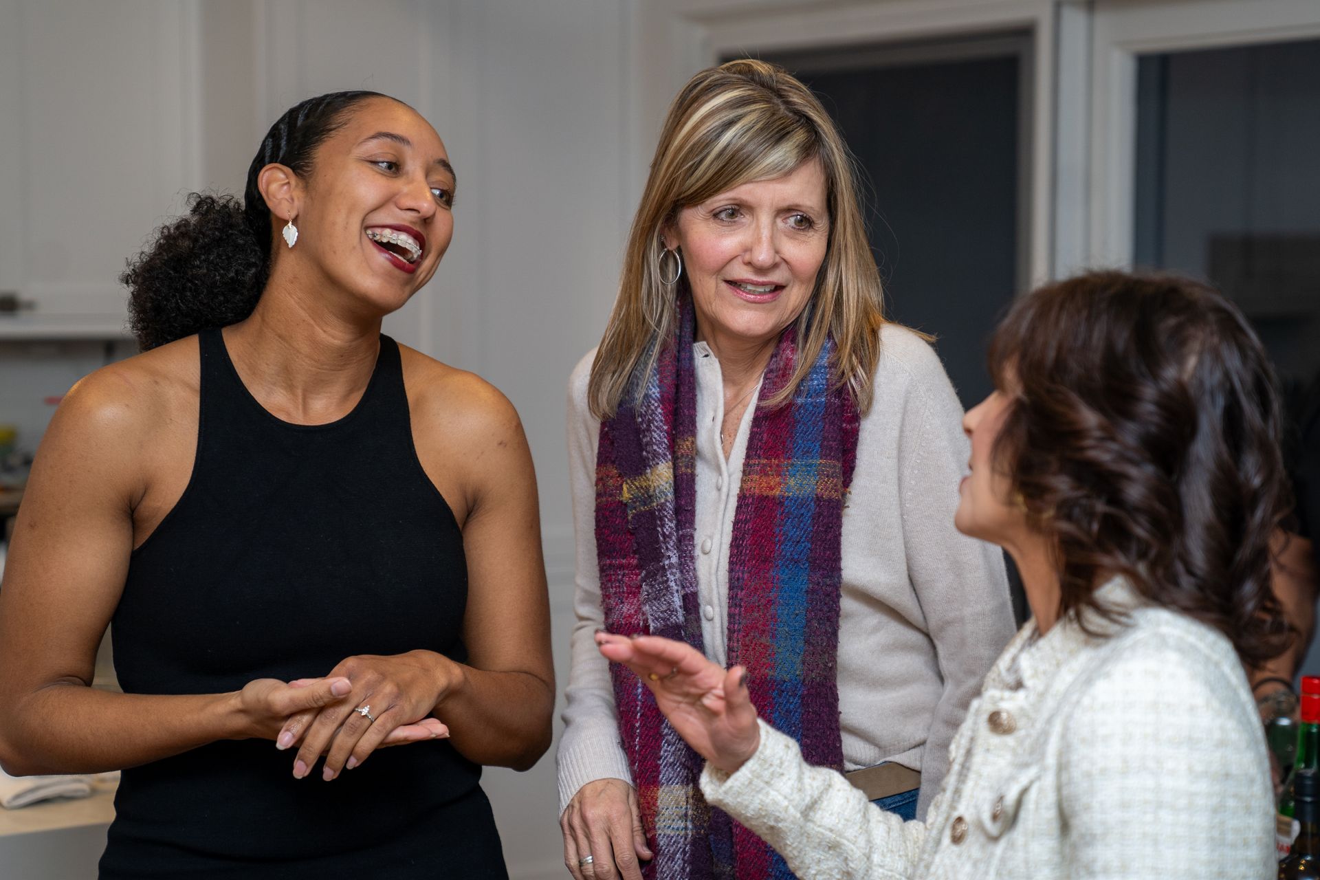 Three women are talking to each other in a room.
