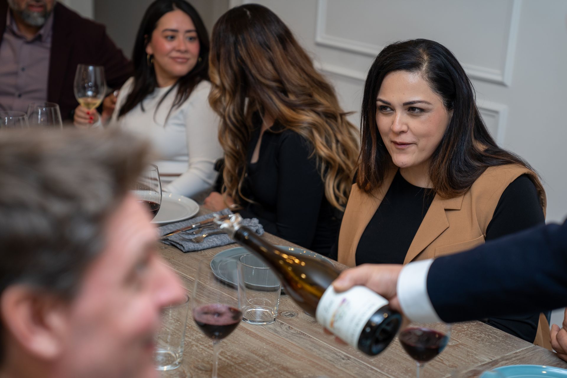 A man is pouring a bottle of wine into a woman 's glass.