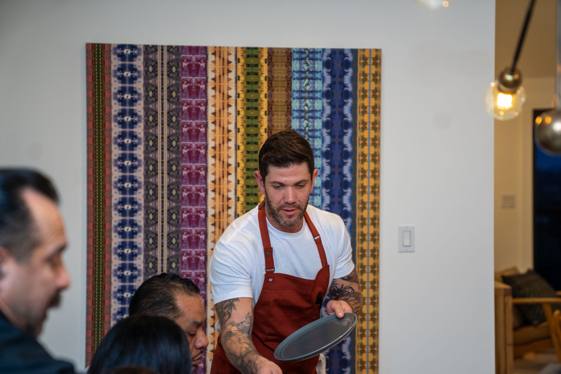 A man in an apron is holding a plate in front of a group of people.