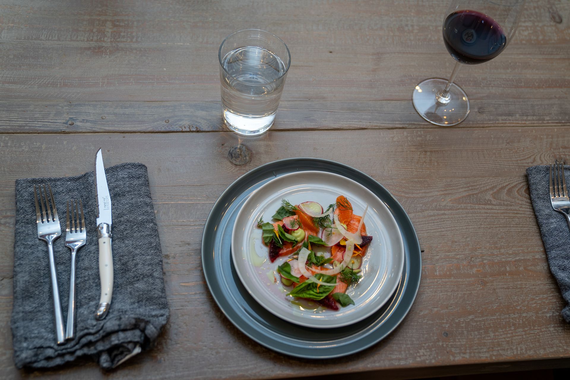 A plate of food and a glass of wine on a wooden table.
