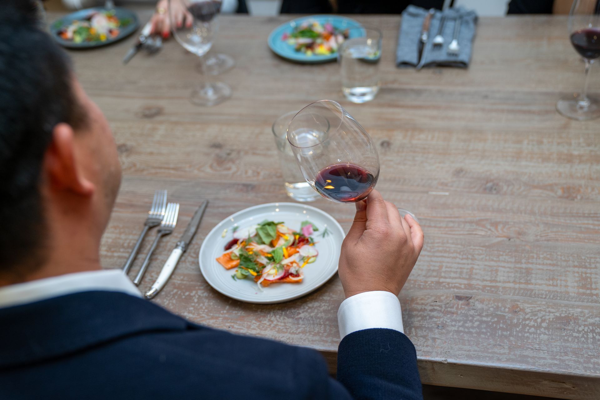A man is sitting at a table with a plate of food and a glass of wine.