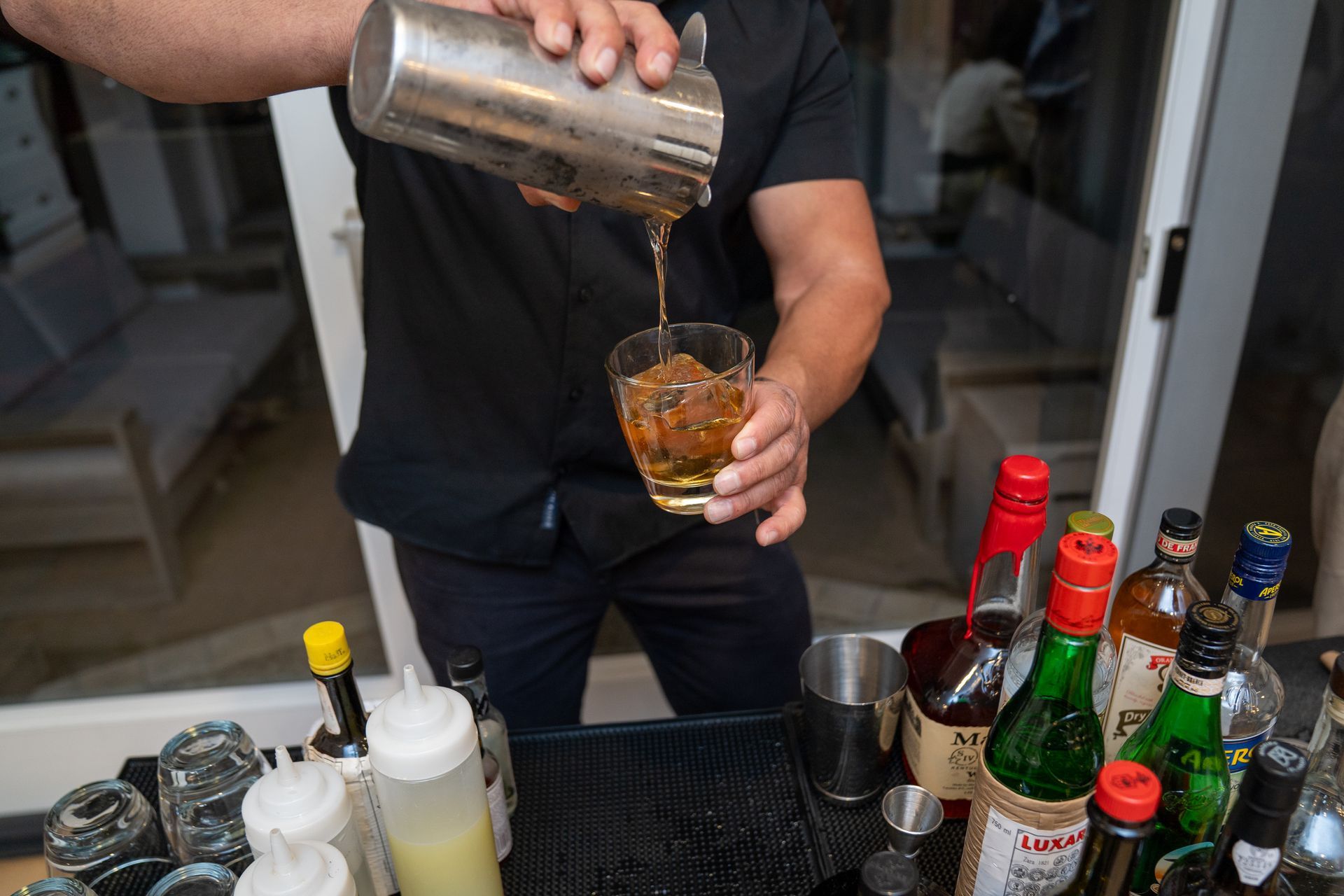 A bartender is pouring a drink into a glass.