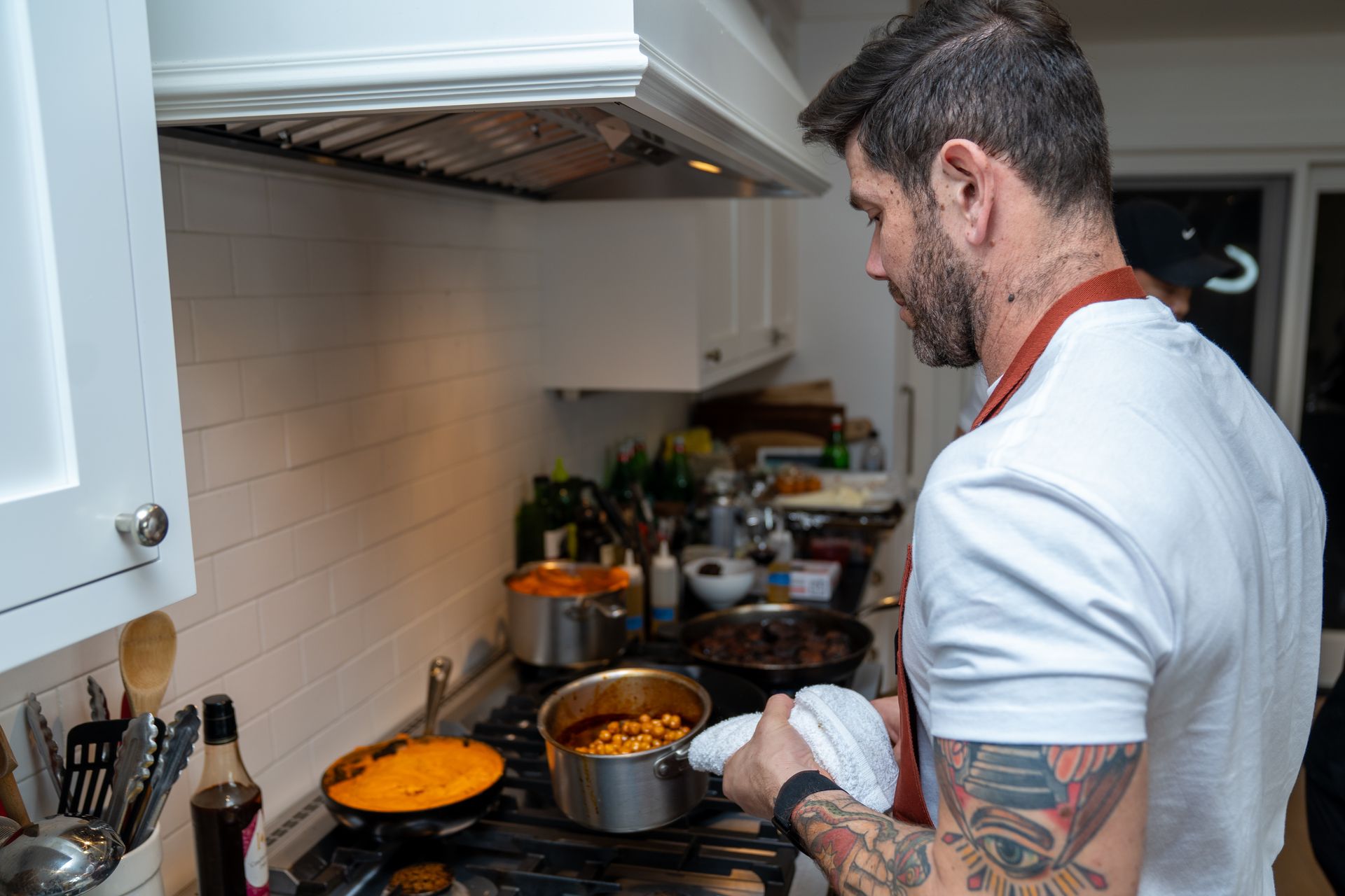 A man is cooking food on a stove in a kitchen.