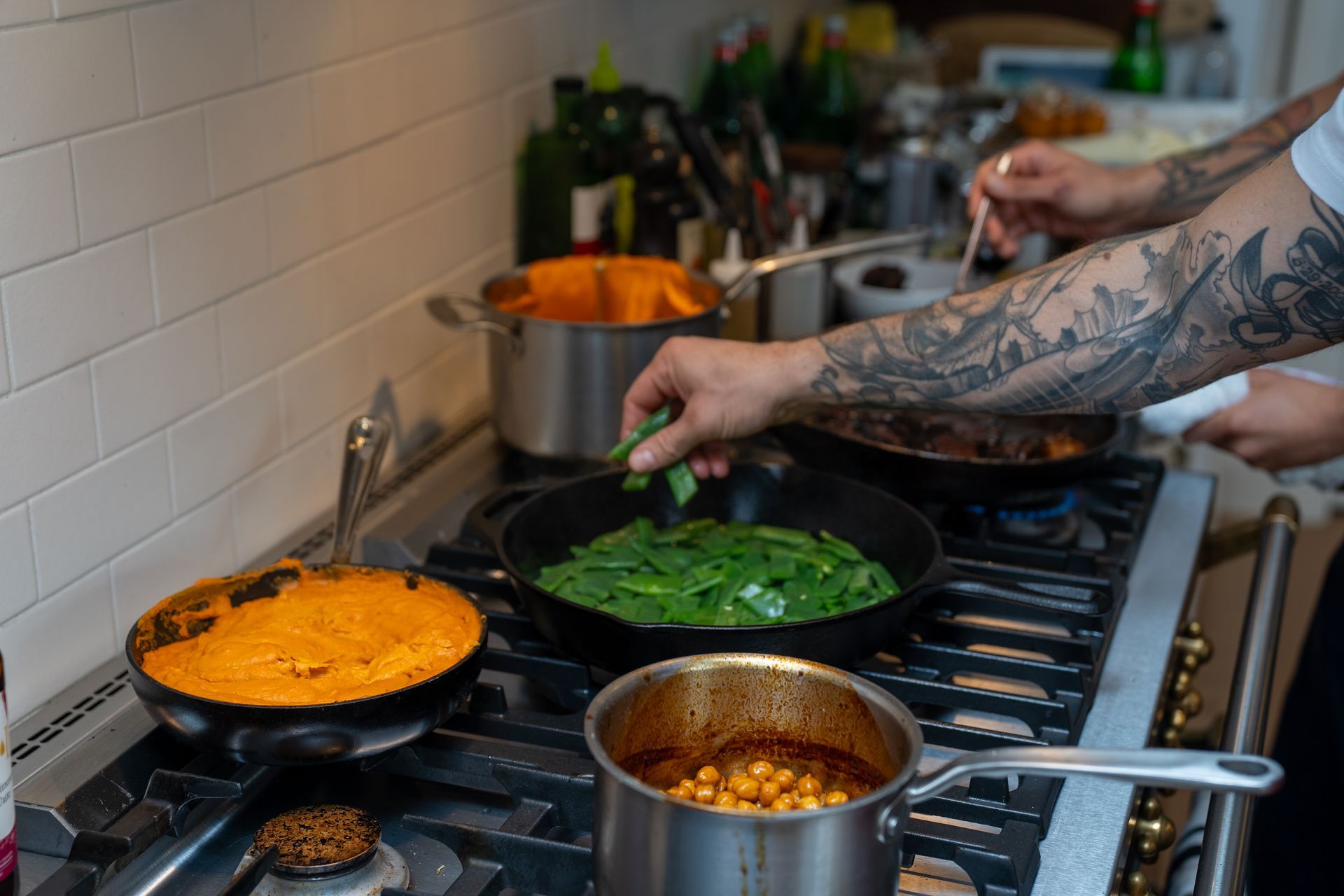 A man is cooking food on a stove in a kitchen.