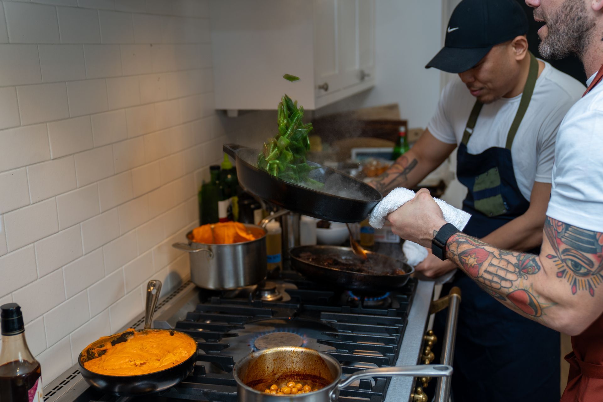 A group of men are cooking food in a kitchen.
