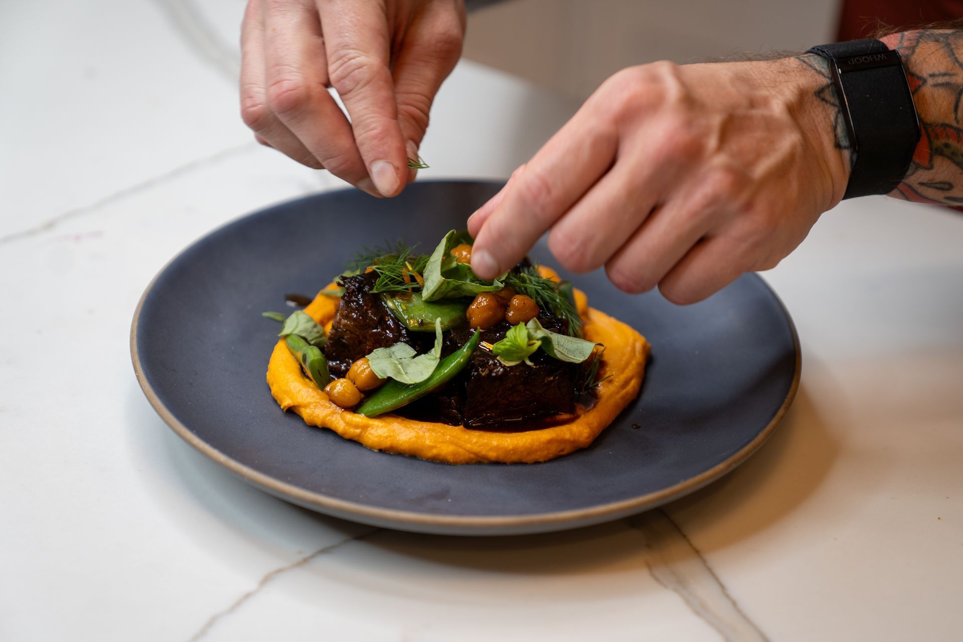 A person is adding vegetables to a plate of food.