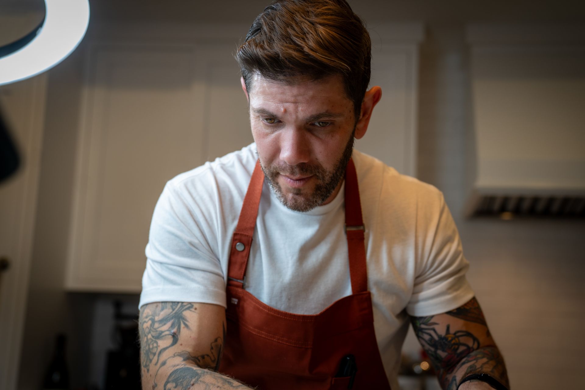 A man wearing an apron and a white shirt is cooking in a kitchen.