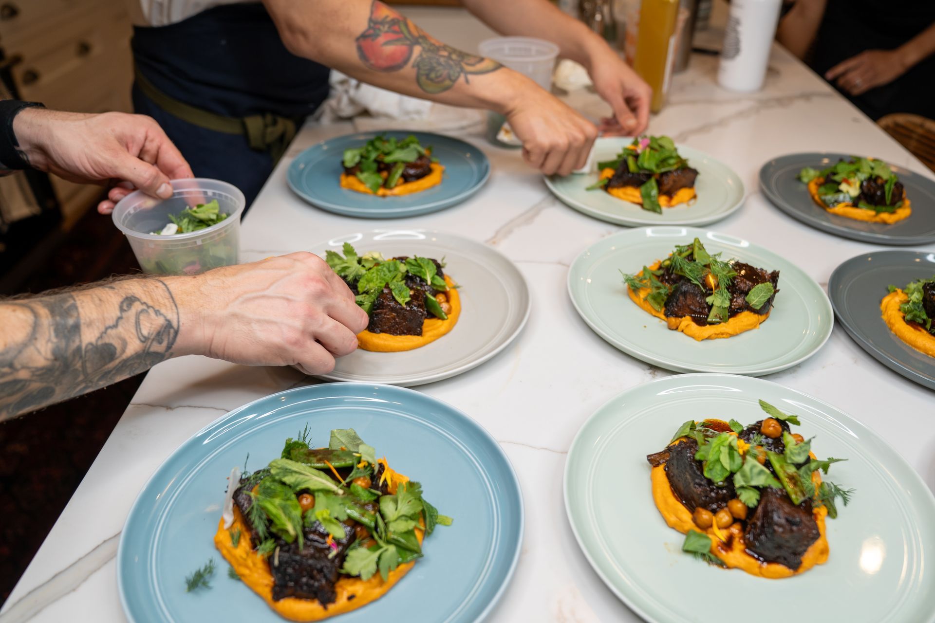 A group of people are preparing food on plates on a table.