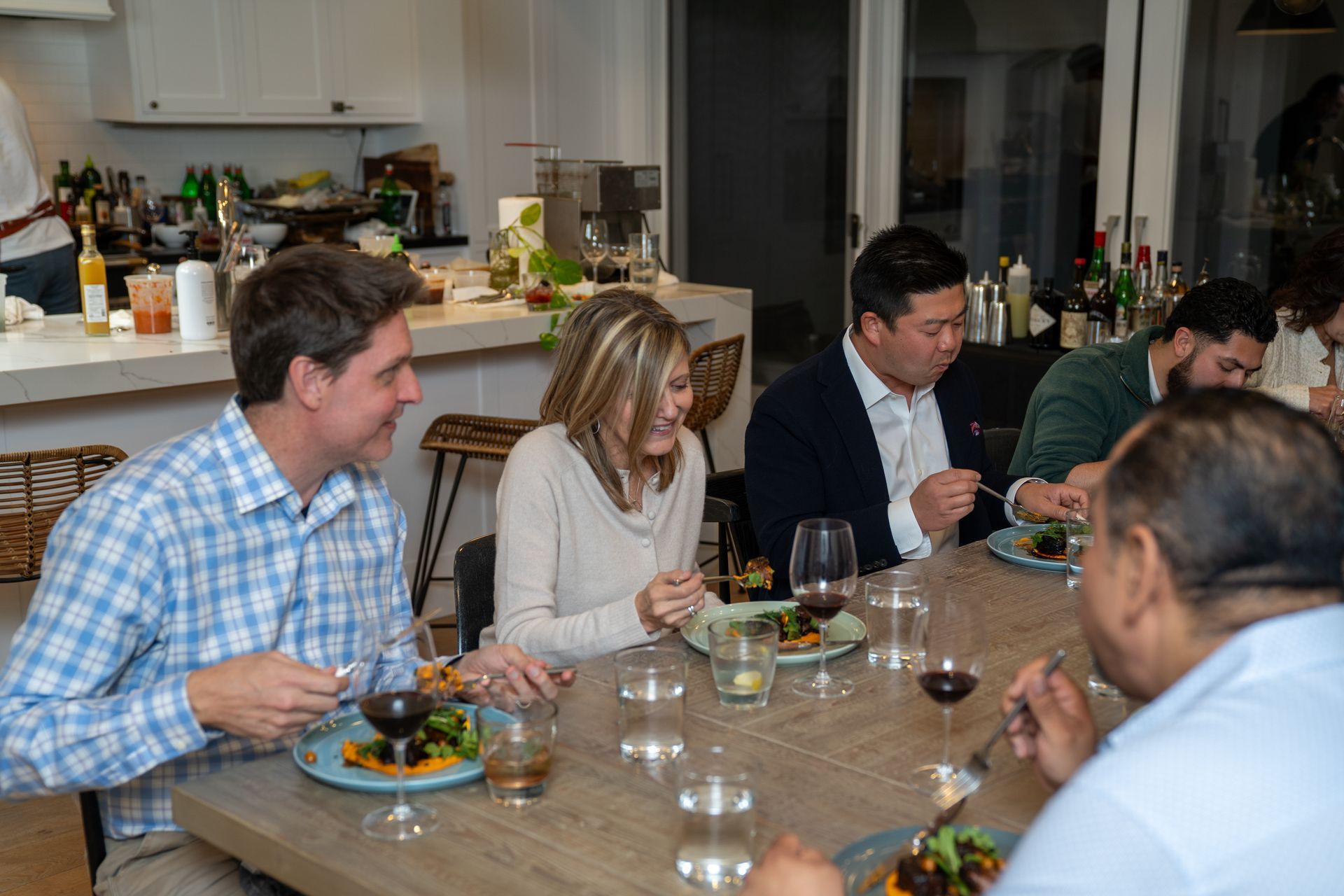 A group of people are sitting at a table eating food and drinking wine.