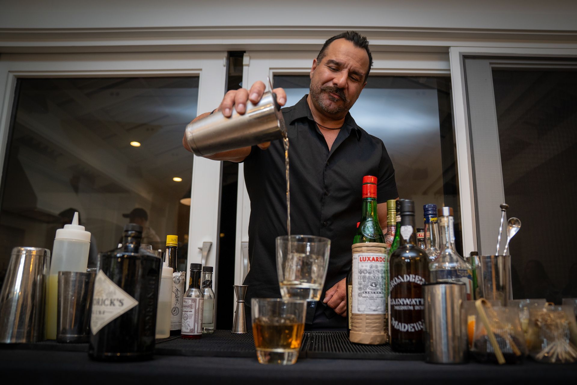 A bartender is pouring a drink into a glass.