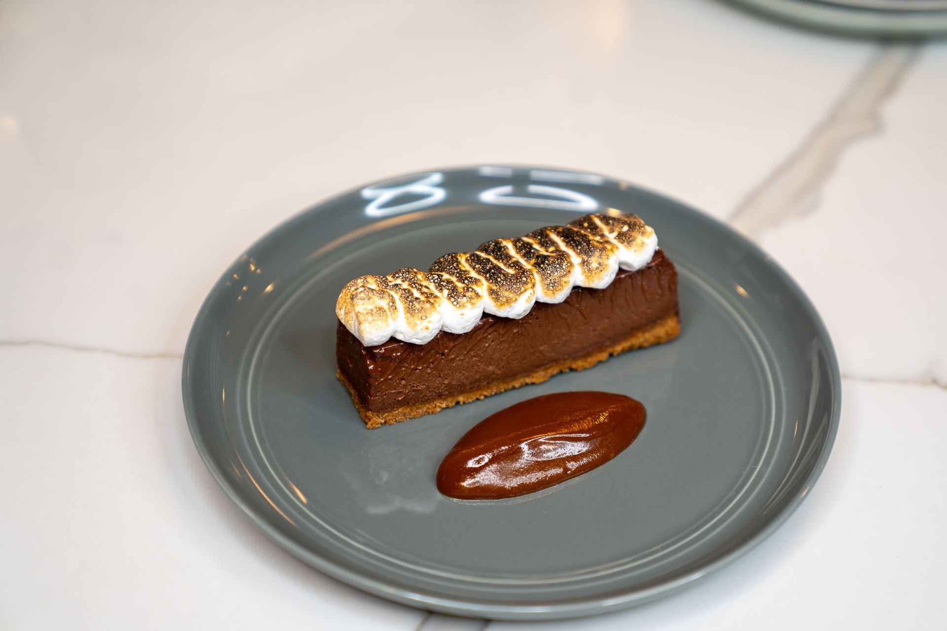 A piece of chocolate cake with meringue on top is on a gray plate.
