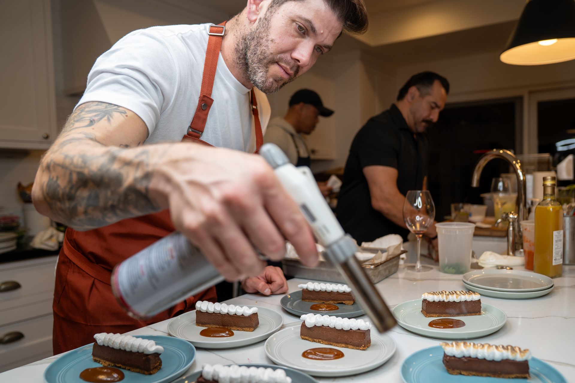 A man is decorating a dessert with whipped cream in a kitchen.