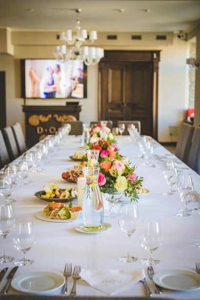 A long table with plates , glasses , and flowers on it.