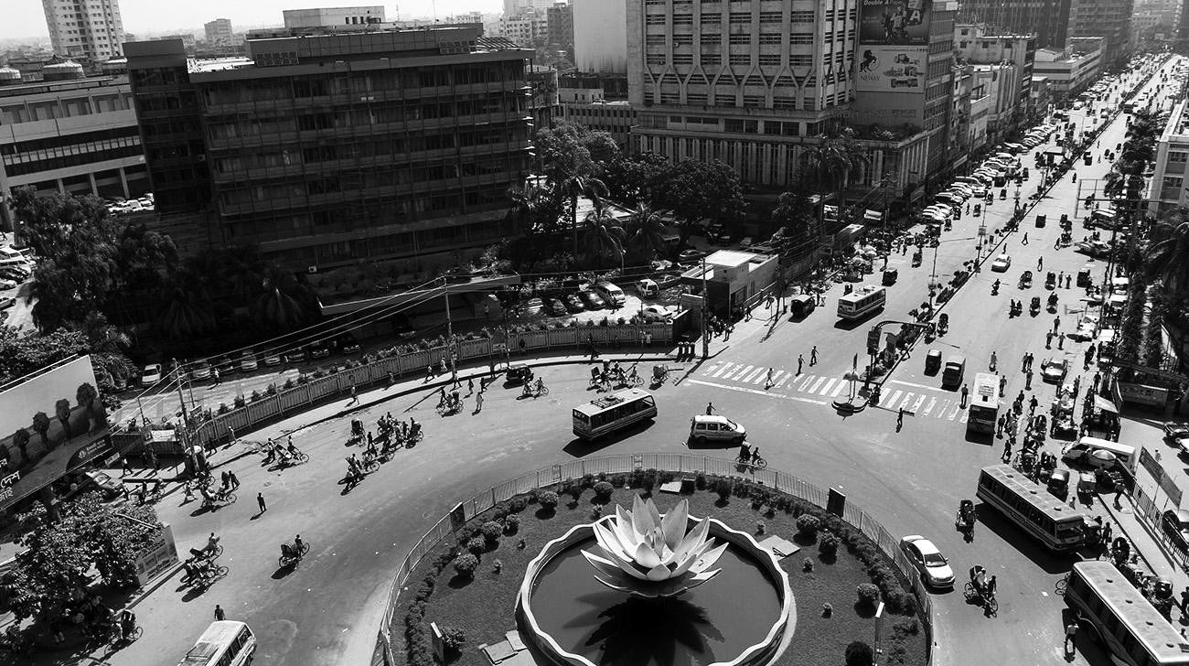 Una foto in bianco e nero di un incrocio cittadino con una fontana al centro